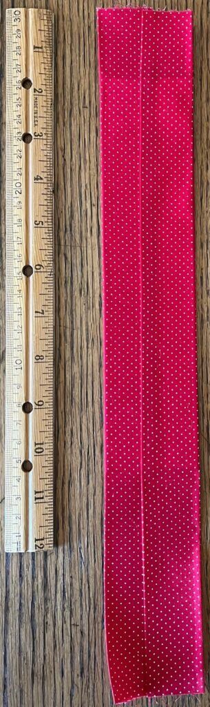 Both sides of fabric folded over mat board, shown next to a ruler